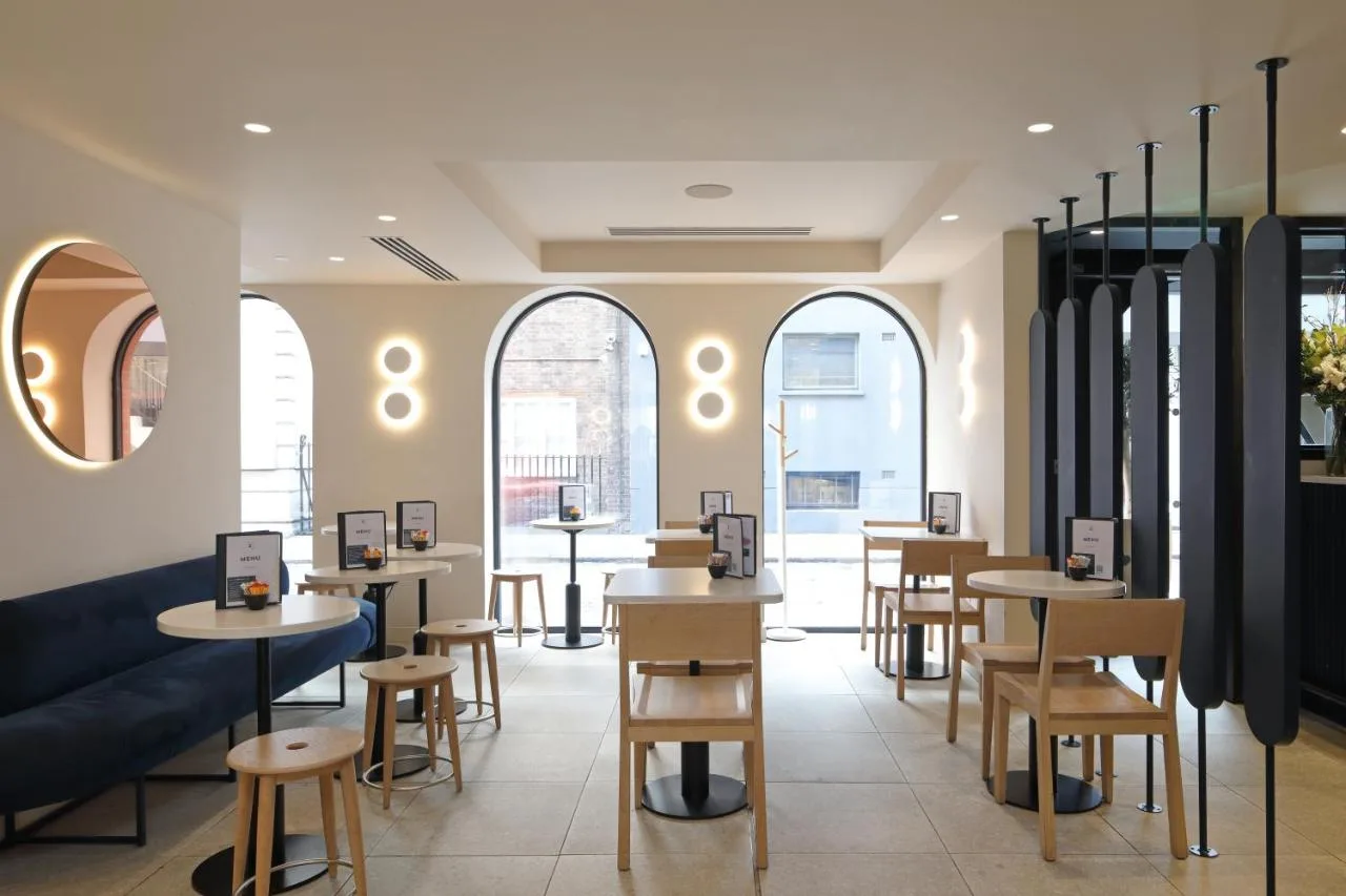 a restaurant with tables and chairs and windows at The Z Hotel Piccadilly in London