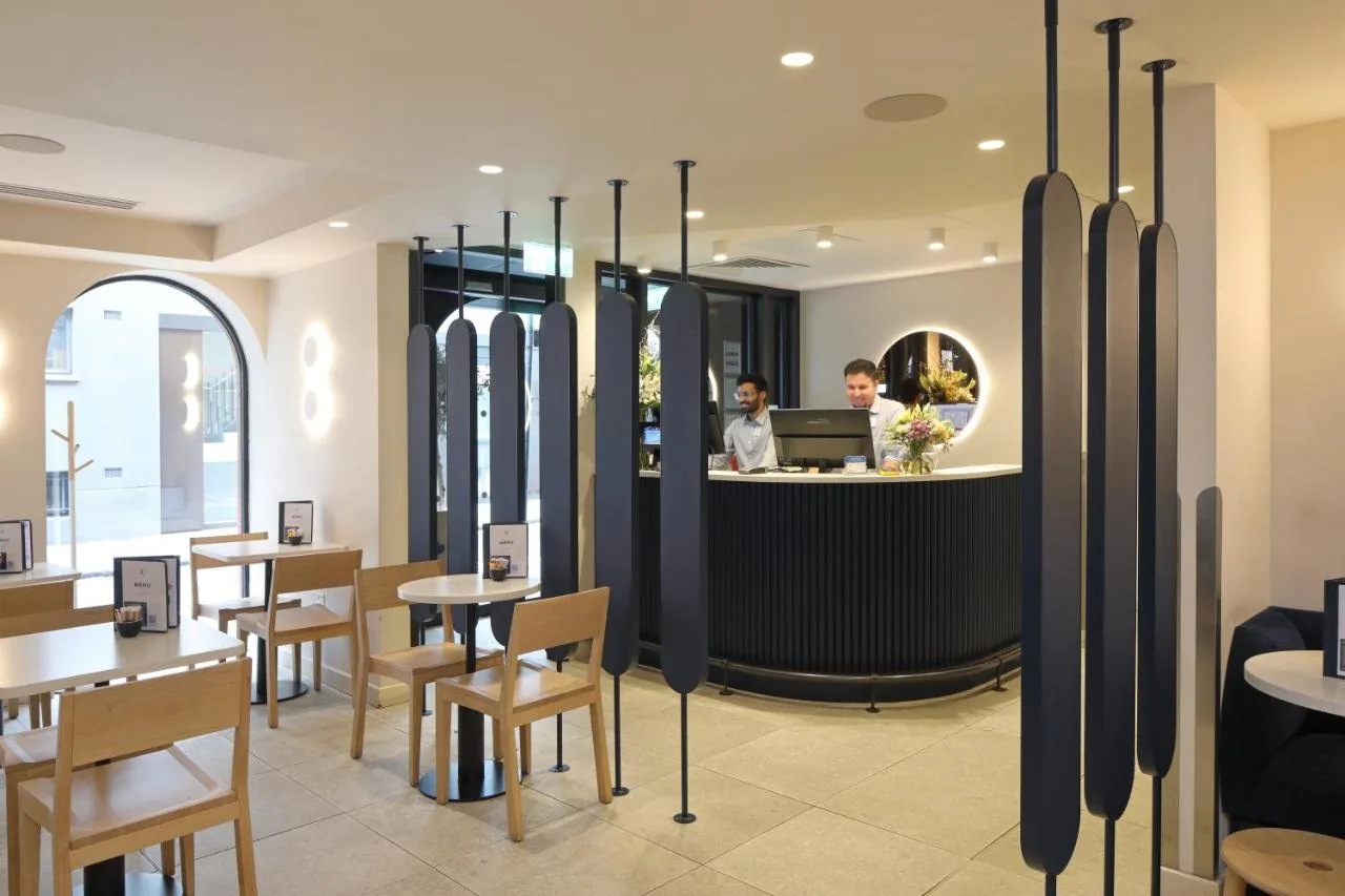 a restaurant with a bar with tables and a woman on a laptop at The Z Hotel Piccadilly in London